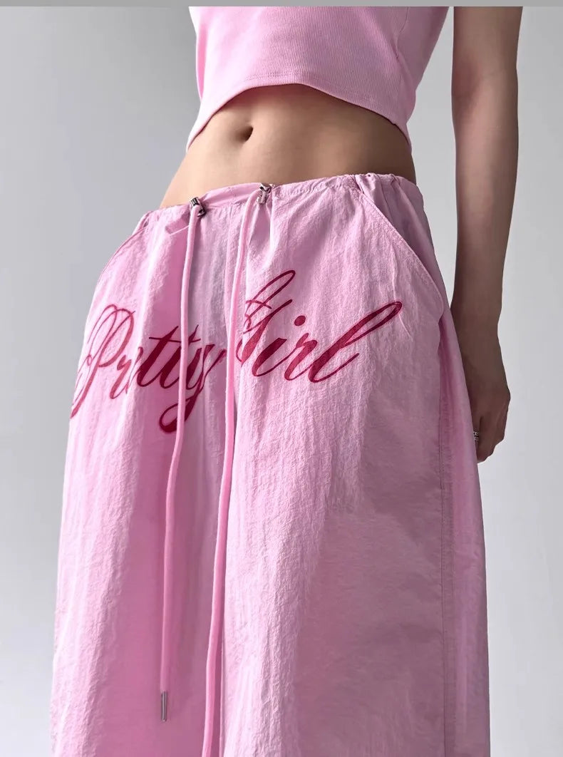 Pink skirt with 'Bitty Girl' text worn by a person on a plain background