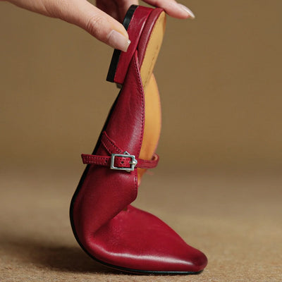Red high-heeled shoe with a strap held by a hand on a beige background