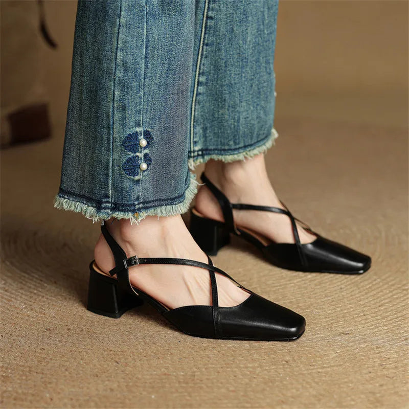 Black block-heel shoes worn with blue jeans on a brown background