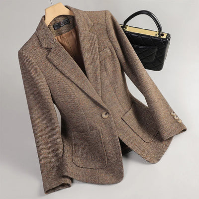 Brown blazer on a mannequin with a black handbag on a light gray background