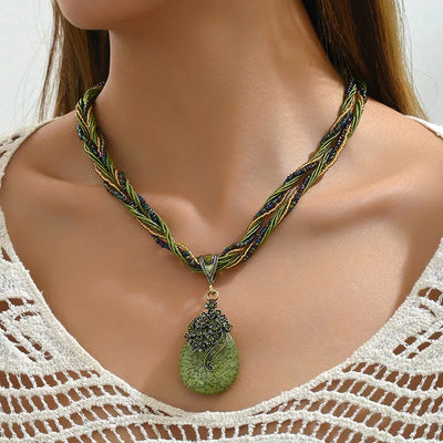 Necklace with a green pendant on a model wearing a white lace top.