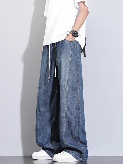 Person wearing wide-leg jeans and a white shirt on a plain background
