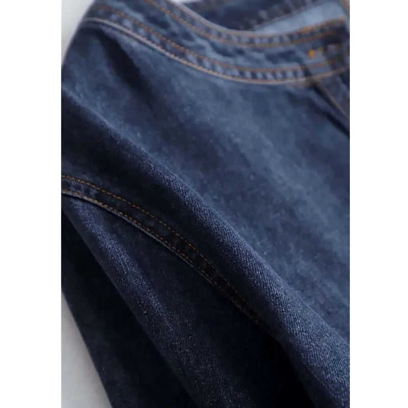 Close-up of blue denim fabric with stitching details on a white background