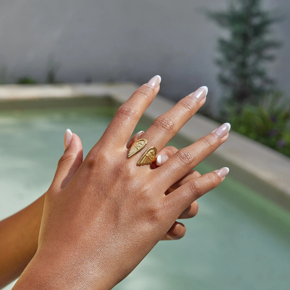 Hand with gold rings against a blurred outdoor background