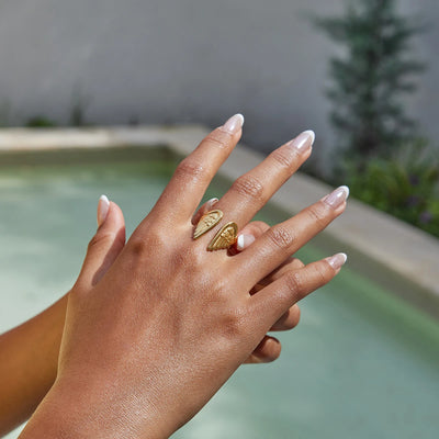 Hand with gold rings against a blurred outdoor background