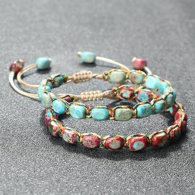 Set of beaded bracelets with turquoise and red stones on a gray background