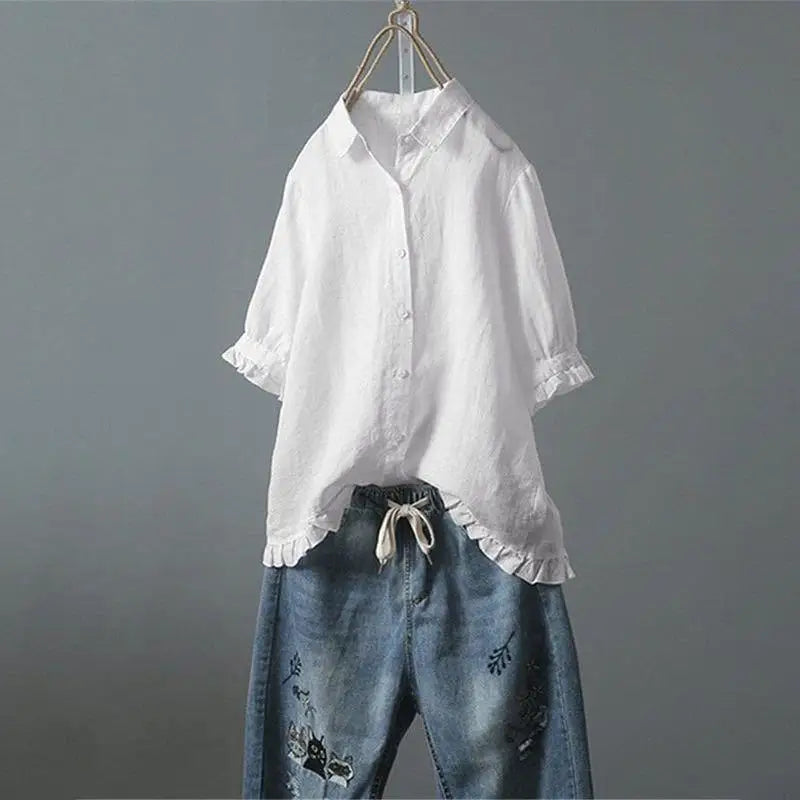 White shirt with ruffled sleeves and blue jeans on a gray background
