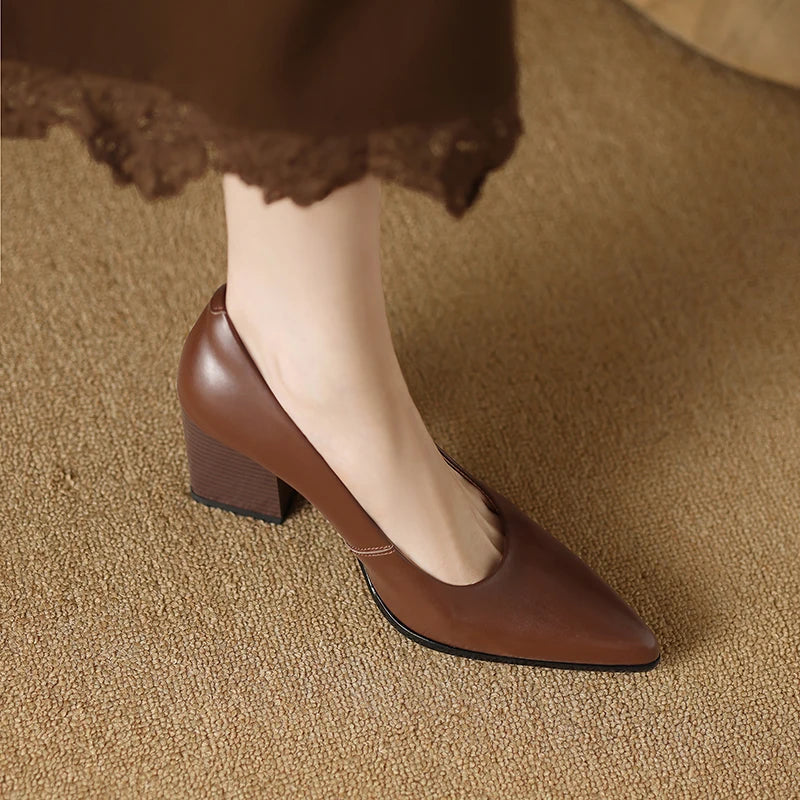 Brown high-heeled shoes worn on a textured brown surface