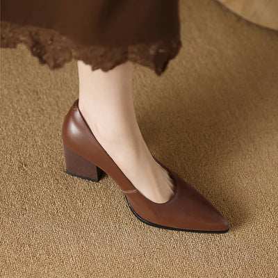 Brown high-heeled shoes worn on a textured brown surface
