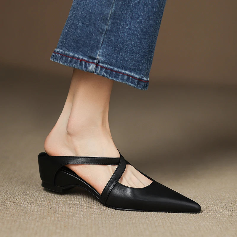 Black leather flat shoe worn with blue jeans on a neutral background