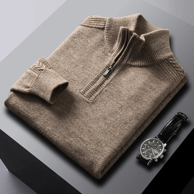 Folded brown sweater on a gray surface with a black watch beside it