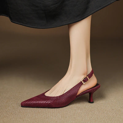 Maroon high-heeled shoes worn with a black skirt on a brown background