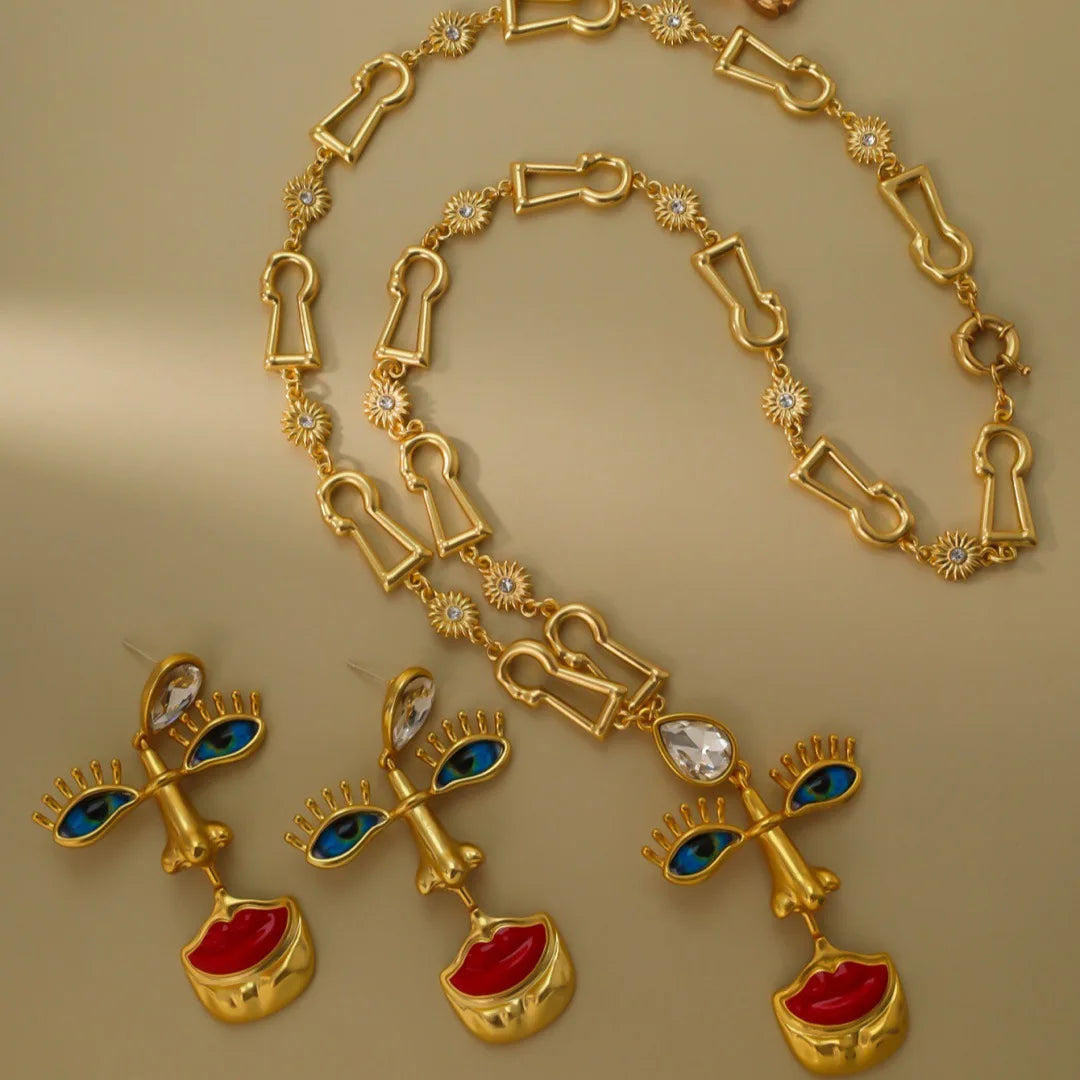 Gold necklace and earrings with red and blue gemstones on a gold background