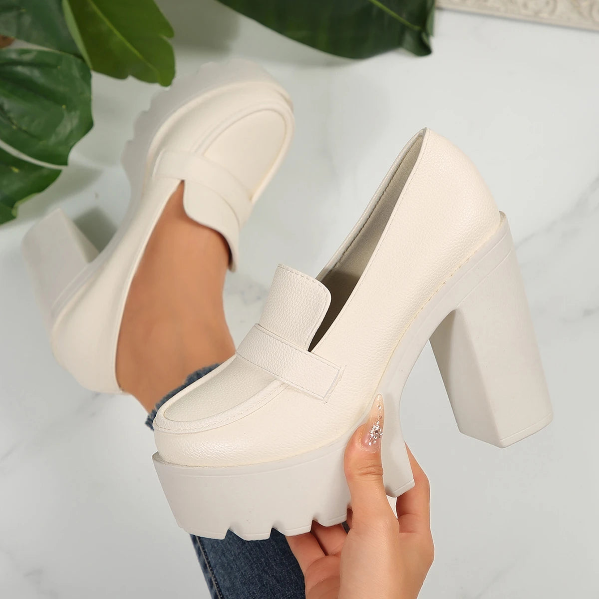 White platform shoes being held with a light gray background
