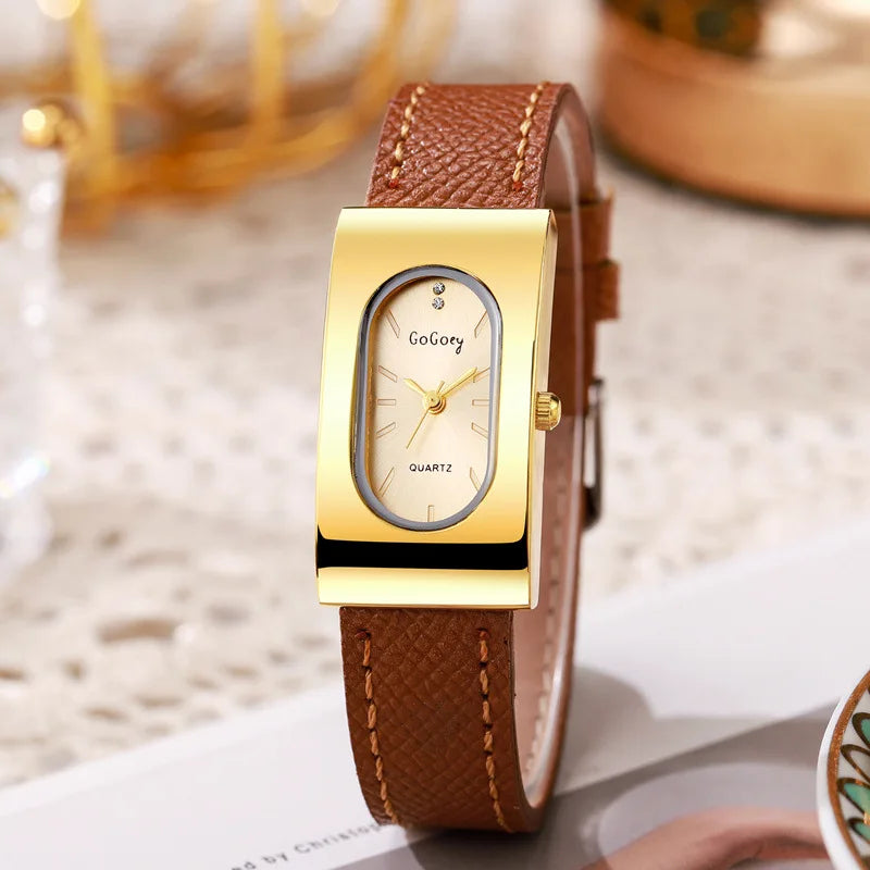 Gold wristwatch with brown leather strap on a blurred background