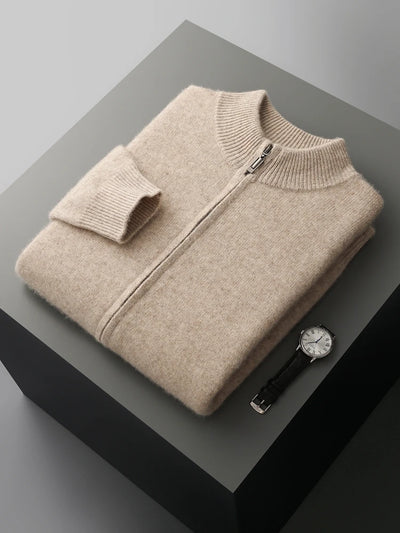 Folded beige sweater on a dark surface with a watch beside it