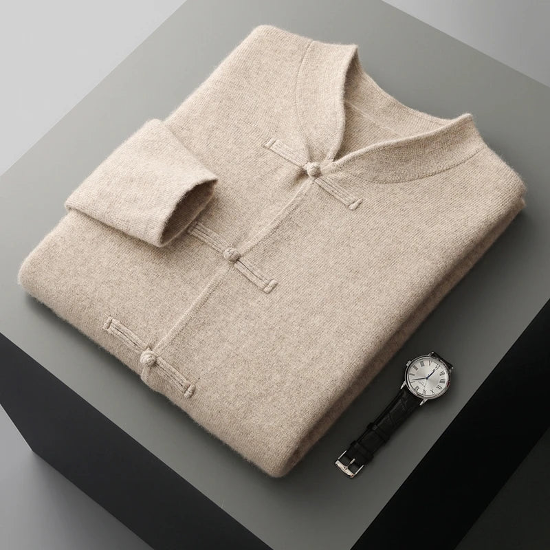 Folded beige sweater with a watch on a gray surface