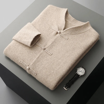 Folded beige sweater with a watch on a gray surface