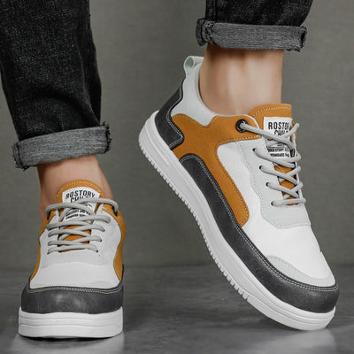 White sneakers with brown and gray accents worn by a person on a gray background