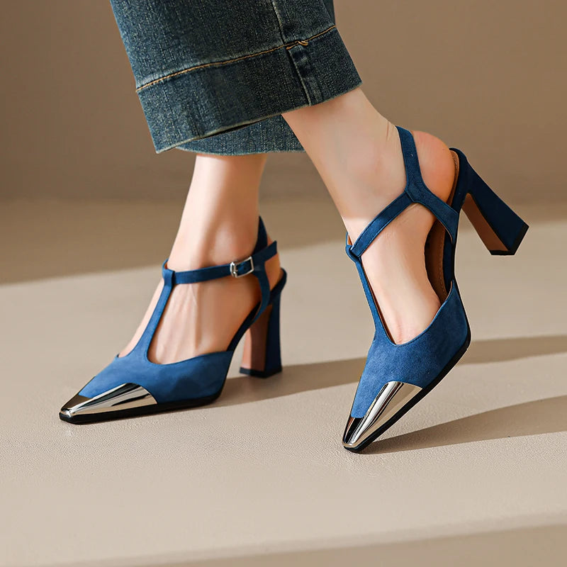 Blue high-heeled shoes with metallic tips worn by a person on a neutral background