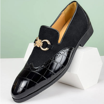 Black loafers with gold accents on a white stand against a light green background