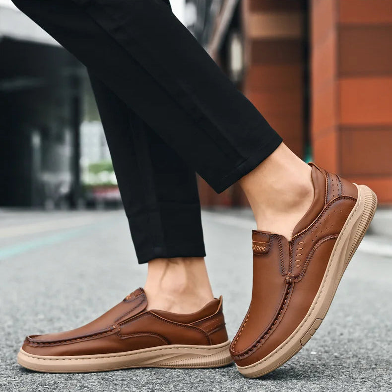 Brown loafers worn with black pants on a blurred street background