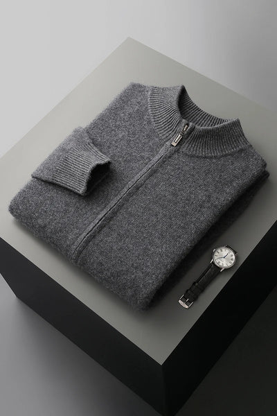 Folded gray sweater on a black and gray surface with a watch beside it