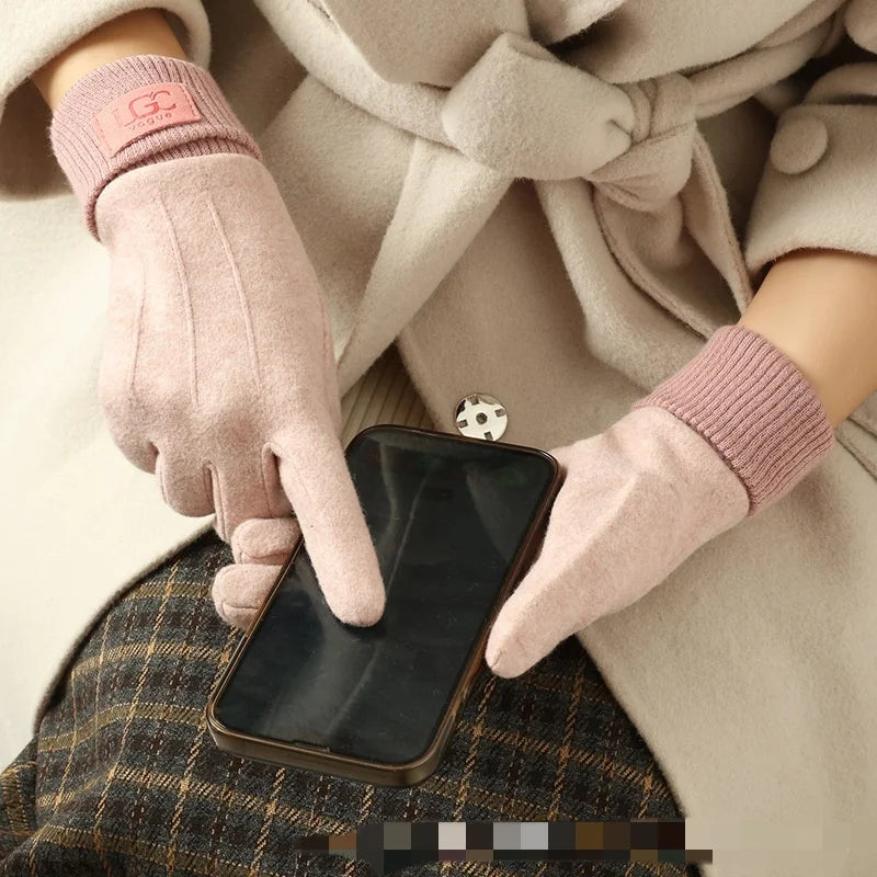 Person wearing pink gloves using a smartphone with a beige coat in the background