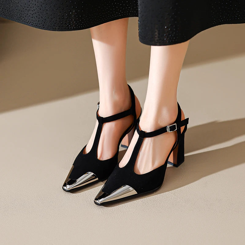 Black high-heeled shoes with metallic accents worn by a person on a neutral background