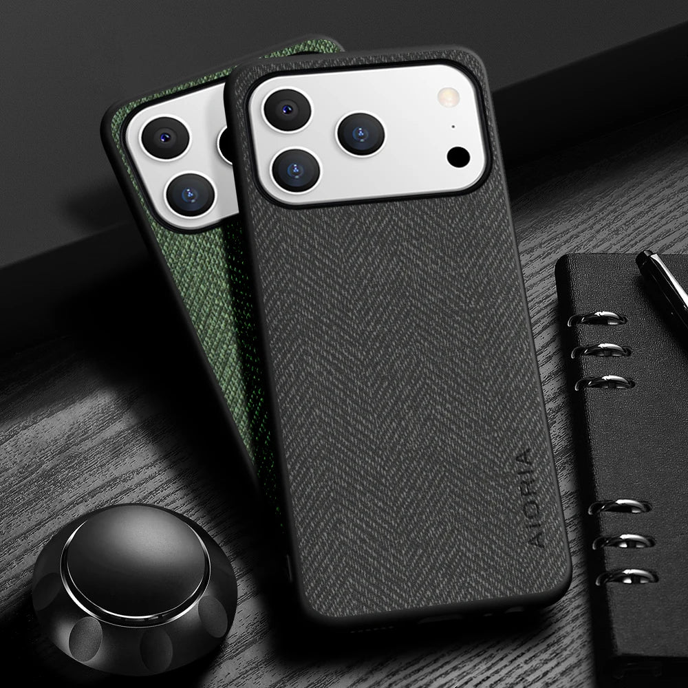 Black phone case with herringbone pattern on a wooden surface with a pen and notebook.