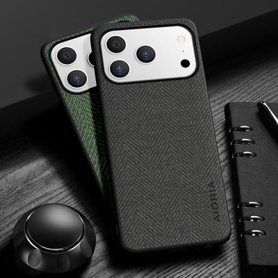 Black phone case with herringbone pattern on a wooden surface with a pen and notebook.