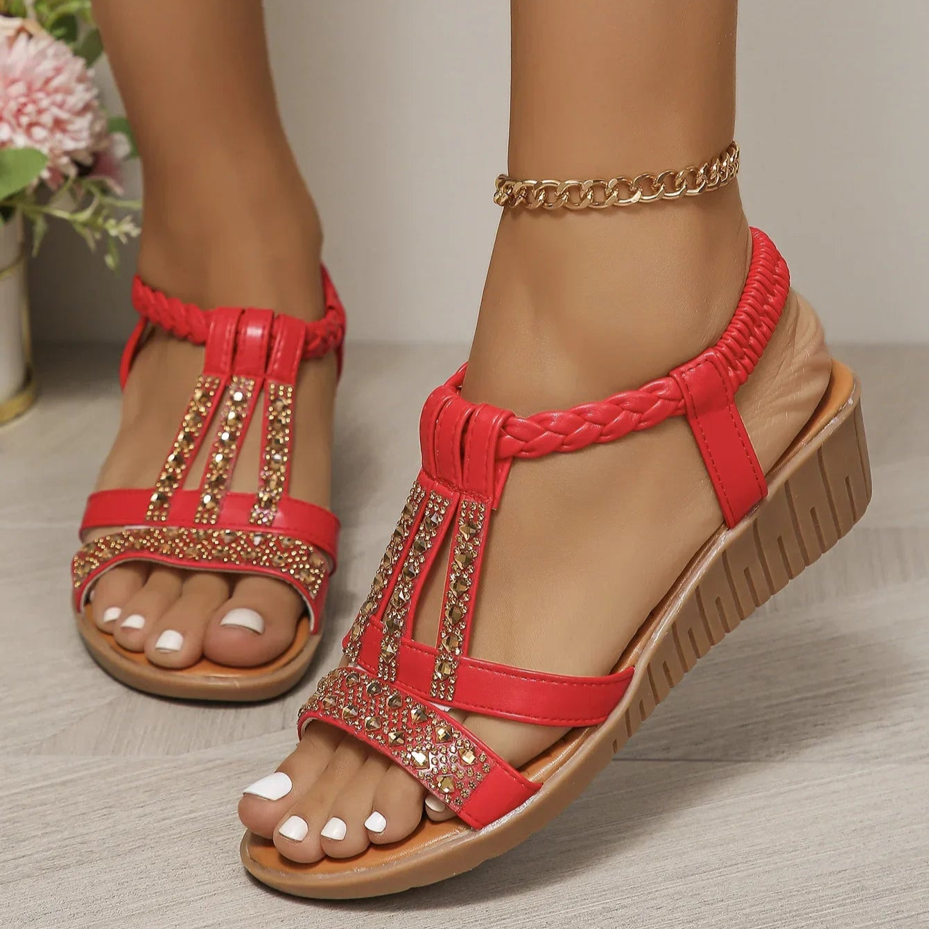 Red sandals with embellishments worn by a person on a neutral background