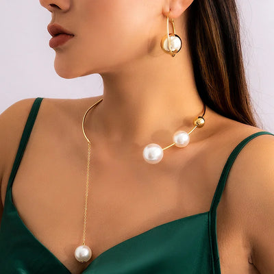Gold necklace with pearl pendants worn by a model against a neutral background