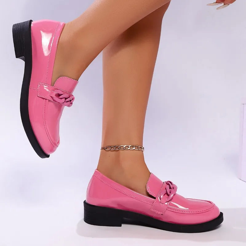 Pink loafers worn on feet with a plain background