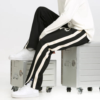 Person wearing black and white striped pants sitting on a metal locker with a white background