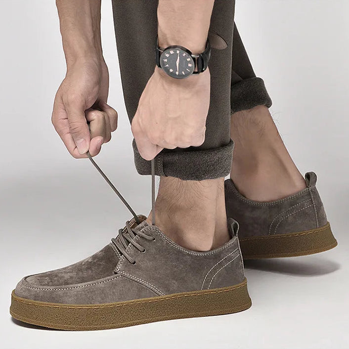 Person wearing brown suede shoes with a plain background