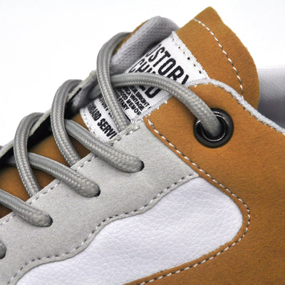 Close-up of a brown and gray sneaker with visible branding on a white background