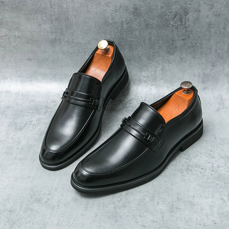 Pair of black leather loafers on a gray concrete surface