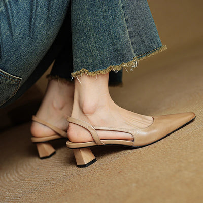 Beige slingback shoes worn with blue jeans on a brown surface