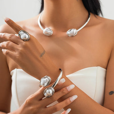 Pearl jewelry set including necklace, earrings, and ring on a model.