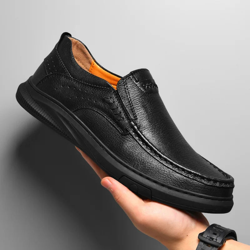 Black leather shoe held in a hand against a gray background
