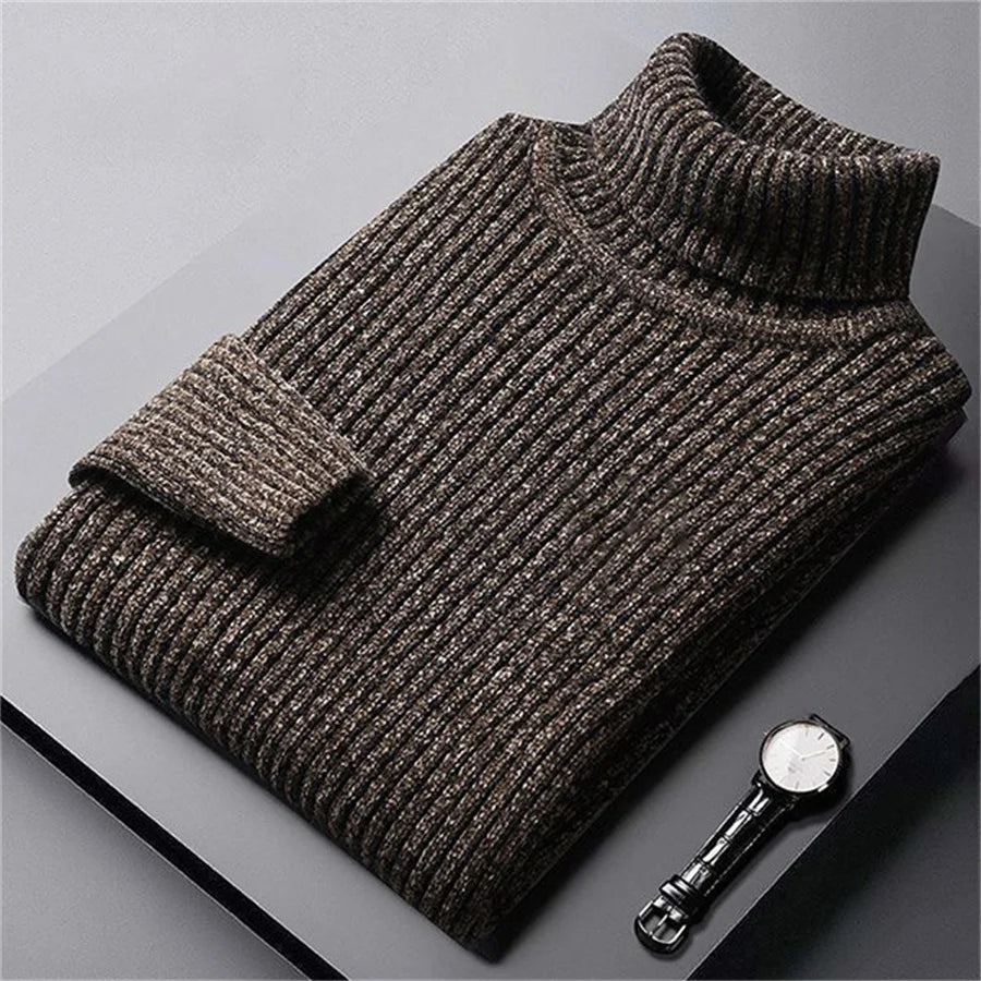 Folded brown sweater on a gray surface with a watch beside it