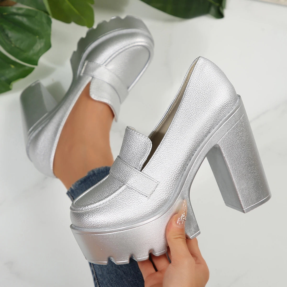 Silver platform shoes being held with a white background