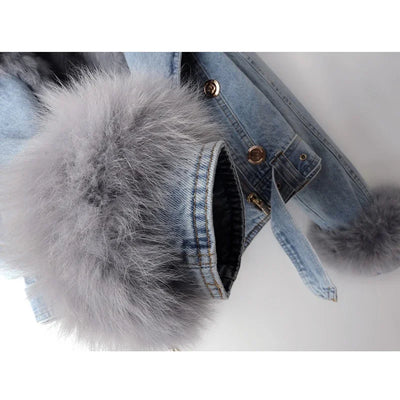 Denim jacket with large fur pom-poms on a white background