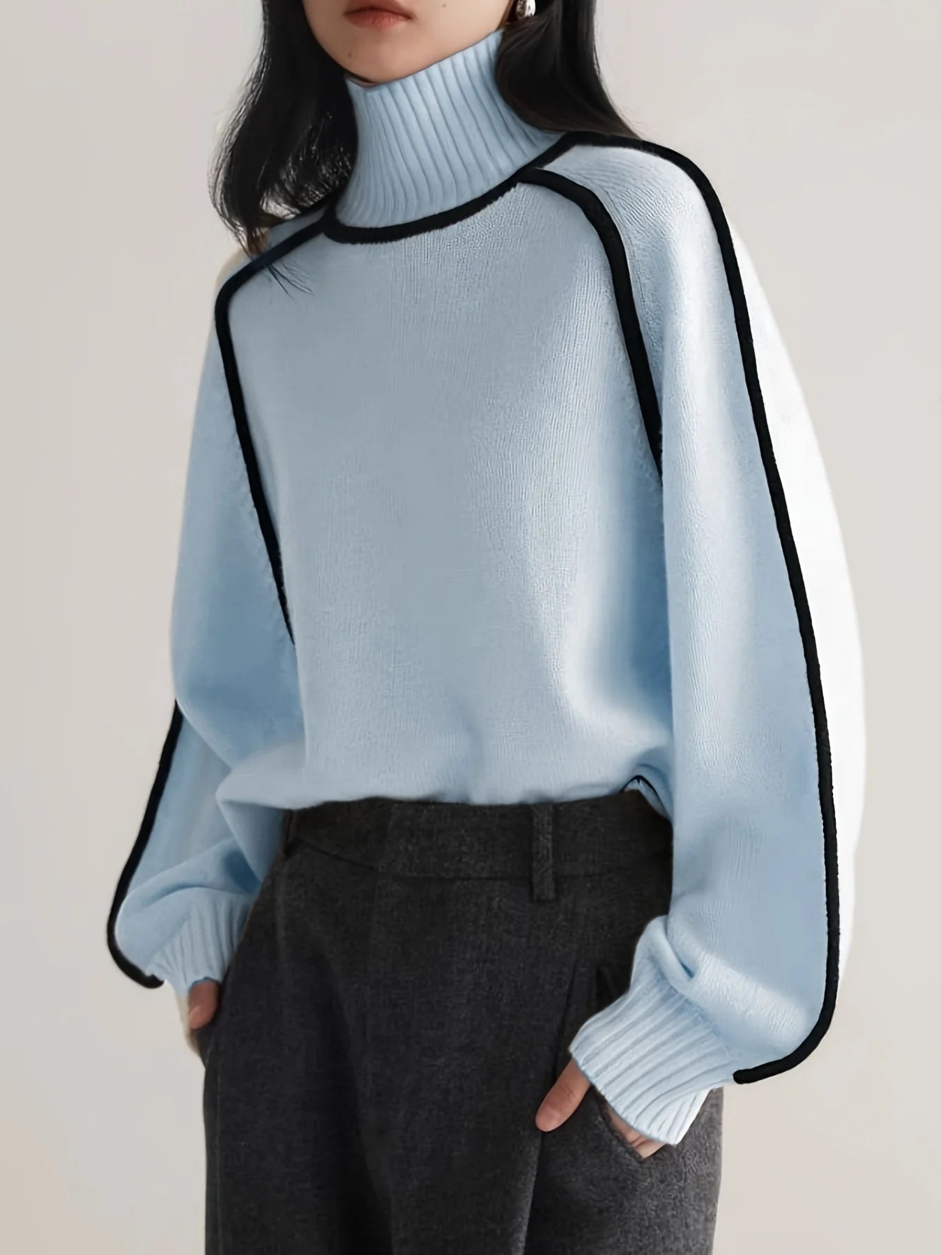 Light blue sweater with black trim worn by a person on a plain background