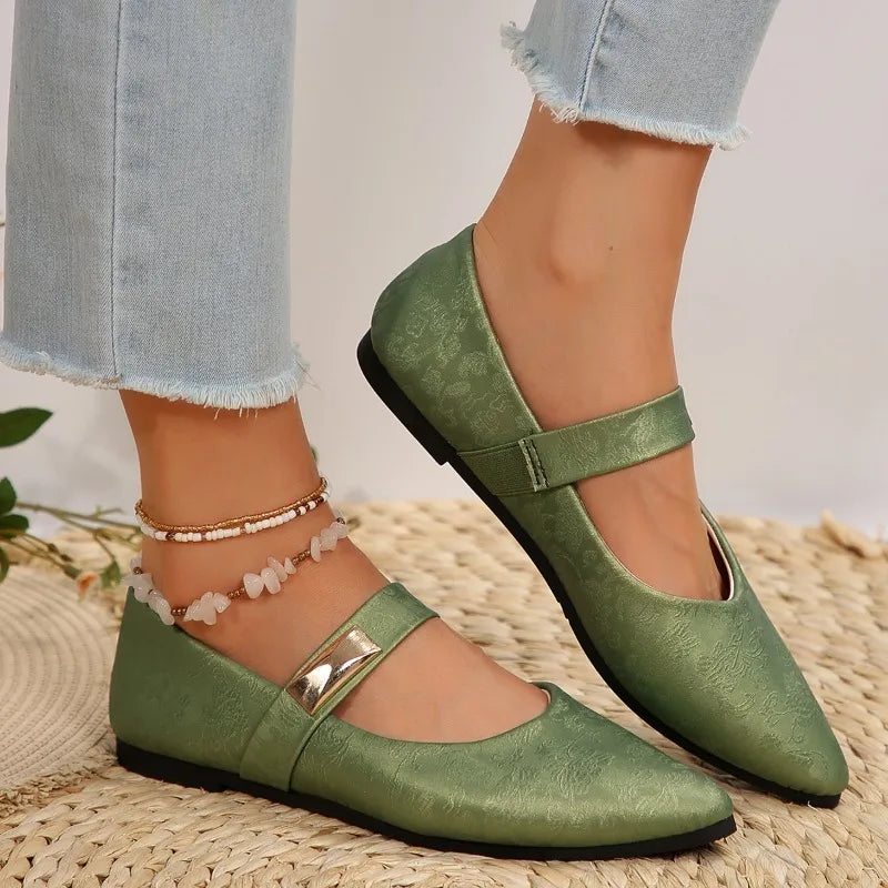 Green flat shoes worn with light blue jeans on a woven surface.