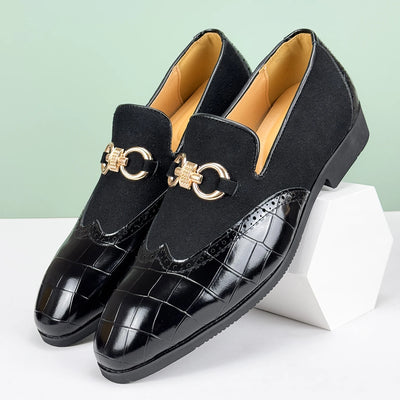 Black loafers with gold accents on a white surface with a light green background