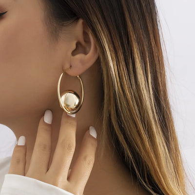 Gold hoop earring worn by a person with a neutral background