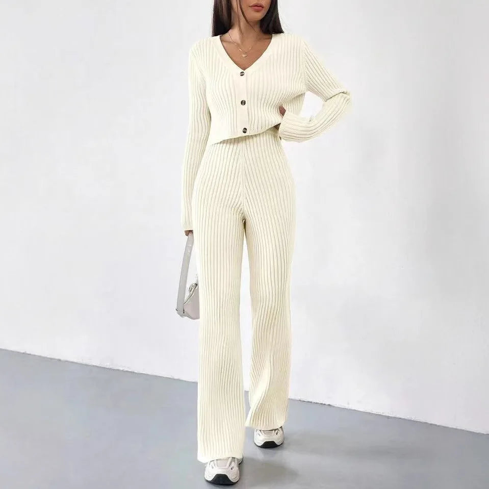 Woman wearing a cream ribbed jumpsuit with a matching cardigan against a white background