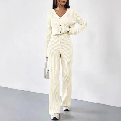 Woman wearing a cream ribbed jumpsuit with a matching cardigan against a white background